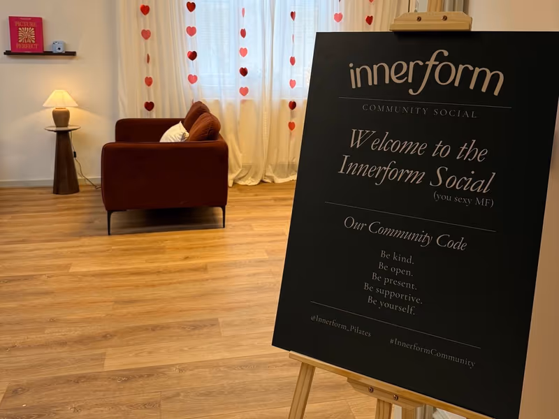 The communal area at Innerform set up for an Innerform Social - welcome easel, heart-string backdrop, low seating, refreshments to one side.
