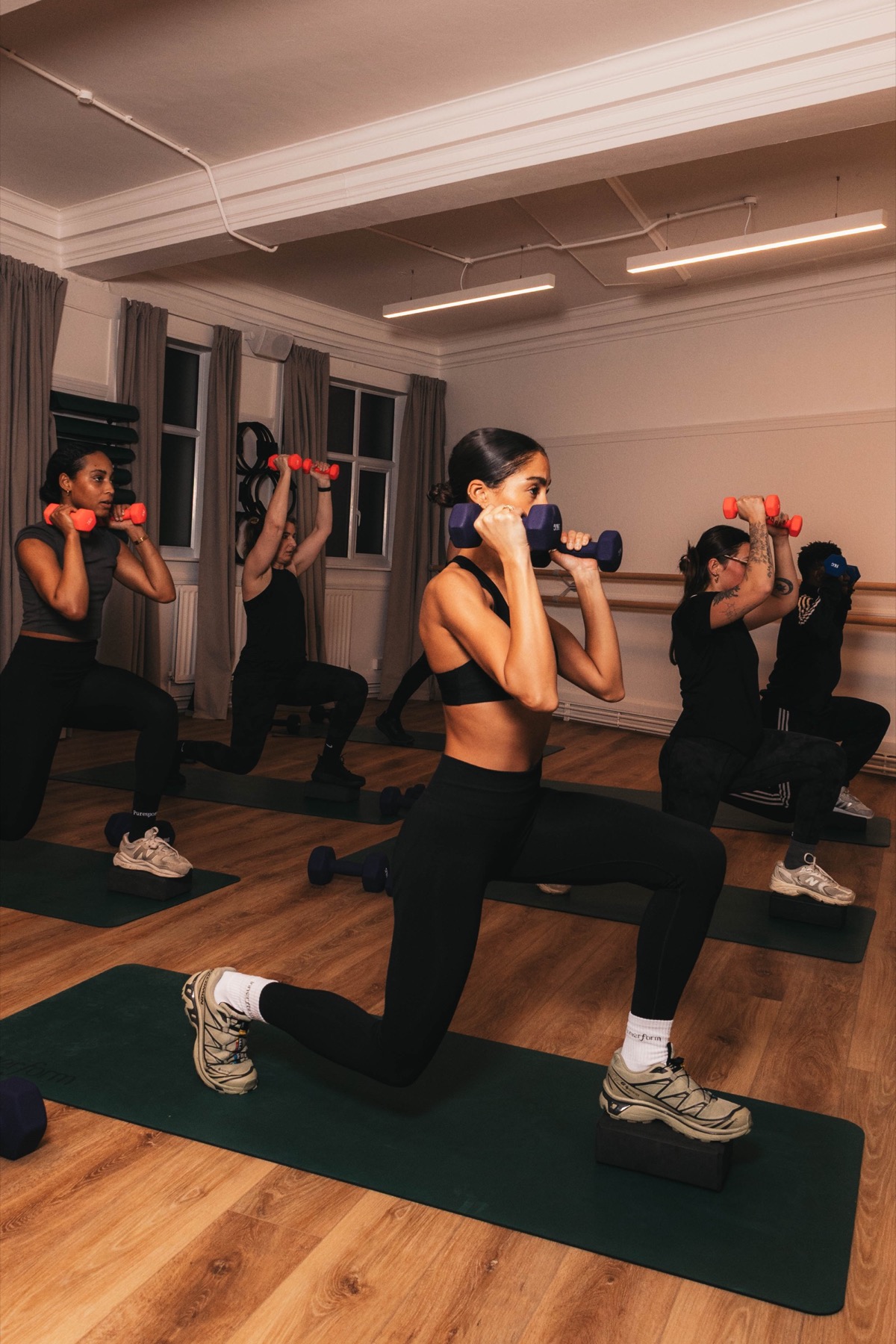 A Small Group Personal Training session at Innerform's Lewisham studio, members lifting dumbbells mid-rep with the coach calling out form.